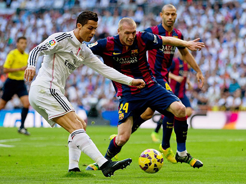 MADRID, SPAIN - OCTOBER 25:  Cristiano Ronaldo of Real Madrid CF looks to cross the ball under pressure from Jeremy Mathieu of Barcelona during the La Liga match between Real Madrid CF and FC Barcelona at Estadio Santiago Bernabeu on October 25, 2014 in Madrid, Spain.  (Photo by Gonzalo Arroyo Moreno/Getty Images)